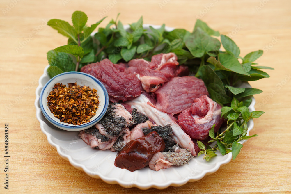 Fresh raw beef and Thai local herbal vegetables, prepare for cooking. Concept, food ingredient. Tradiotnal weird food. Popular menu in northern of Thailand.  Local food. Food ingredients to cook Larb.