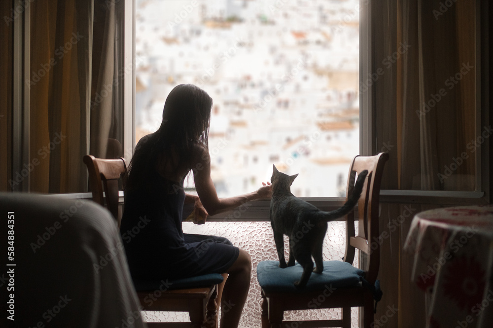 Woman caressing cat near the window