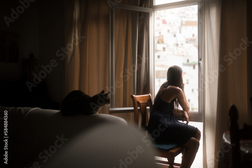 Bored woman and cat looking through window on crowded town