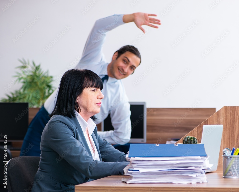 Two employees doing sport exercises in the office Two employees doing sport exercises in the office