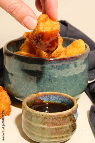 hand dipping nugget in sauce