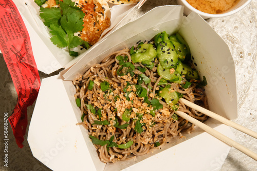 Soba noodle salad dish from food truck cart in to-go packaging. 