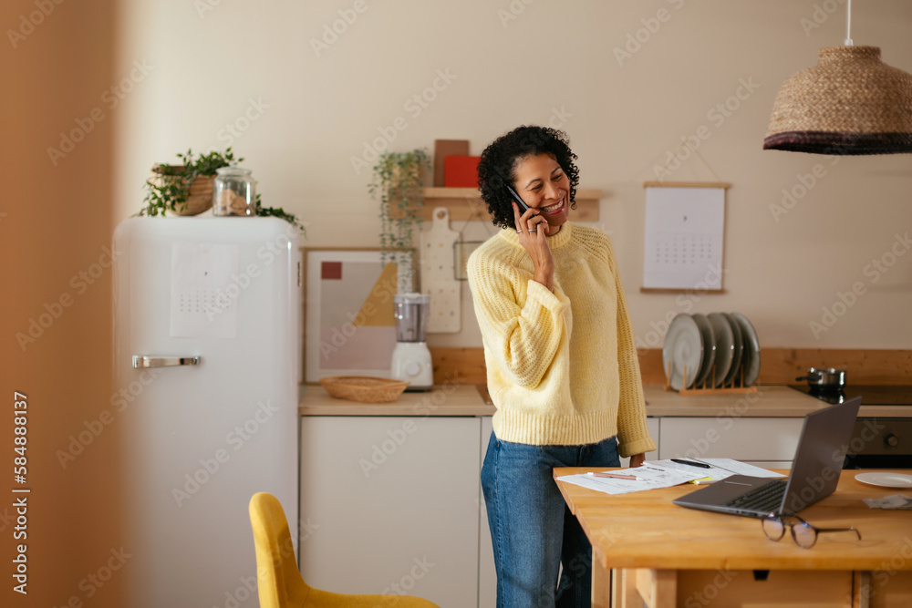 Smiling woman talking on smartphone in kitchen Smiling woman talking on smartphone in kitchen