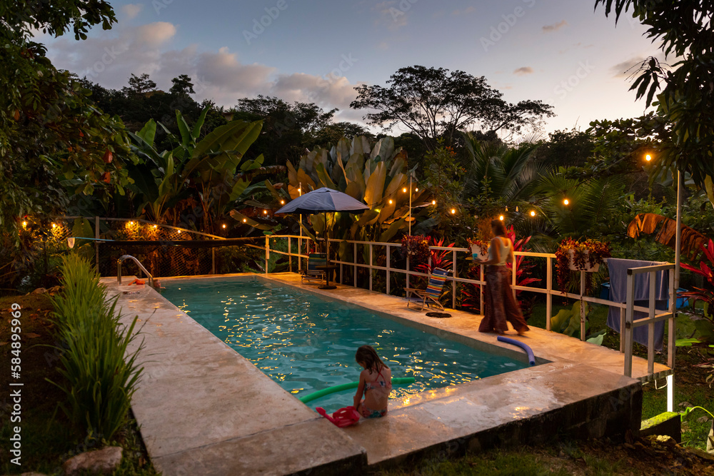 © Raymond Forbes LLC/Stocksy - Sunset at swimming pool with family together in Costa Rica