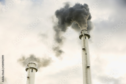 Dark smoke flowing from factory chimney at sunset