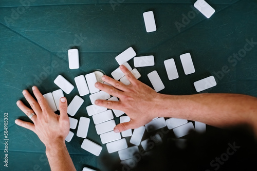 Overhead photo of a man shuffling dominoes