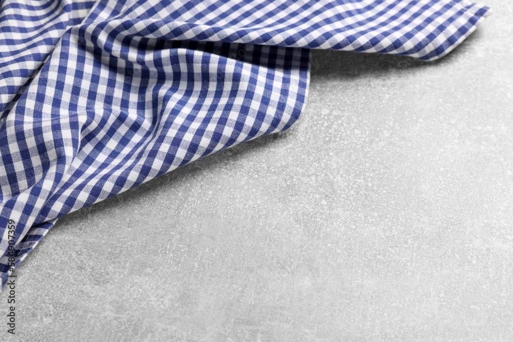 Blue checkered tablecloth on light gray textured table, space for text Blue checkered tablecloth on light gray textured table, space for text
