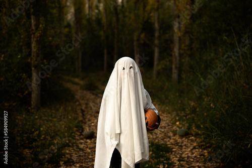 child hiding under a sheet on halloween
