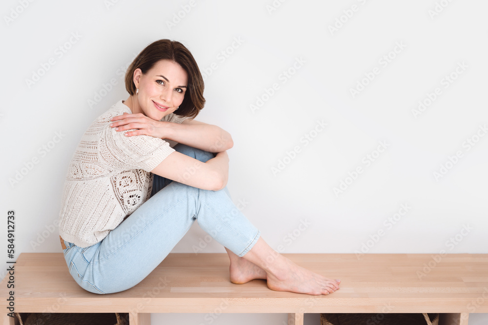 Naturally beautiful young woman sitting on a bench hugging her knees. Naturally beautiful young woman sitting on a bench hugging her knees.