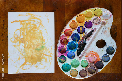 Watercolor palette and a yellow aquarelle painting. photo