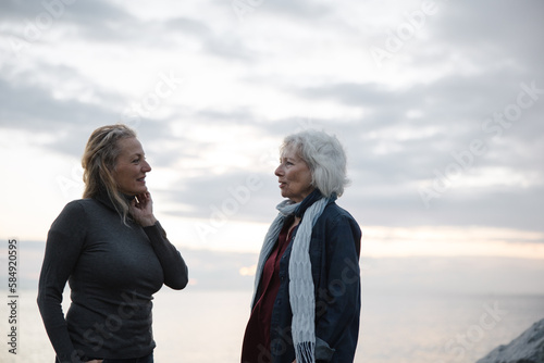 Two mature women talking together near the ocean. photo