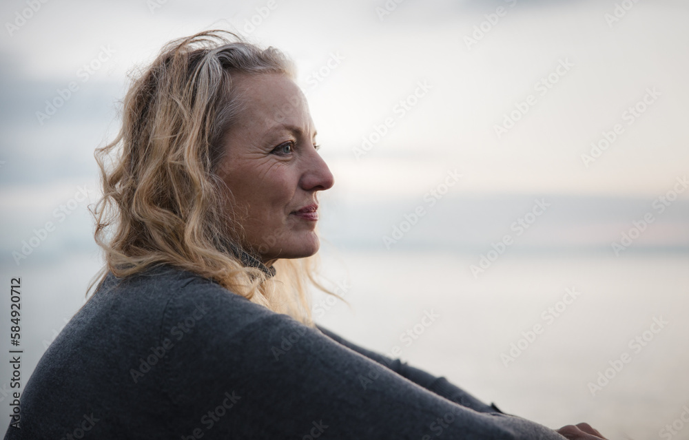 Thoughtful mature woman looking out at sunset. Thoughtful mature woman looking out at sunset.