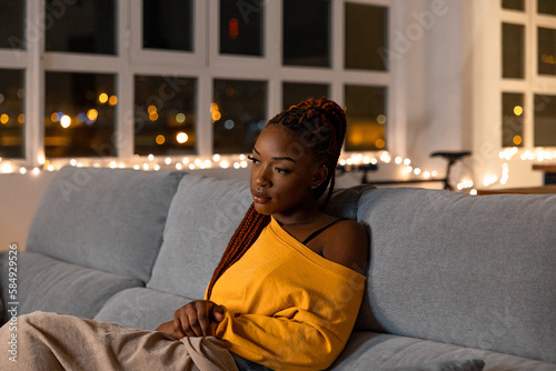 calm young black woman on the sofa watching a movie at night photo