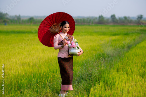 Pretty Asian women in traditional Thai dress. Beautiful traditional Thai dresses by Asian Buddhists make merit at the Temple a tourist attraction, a