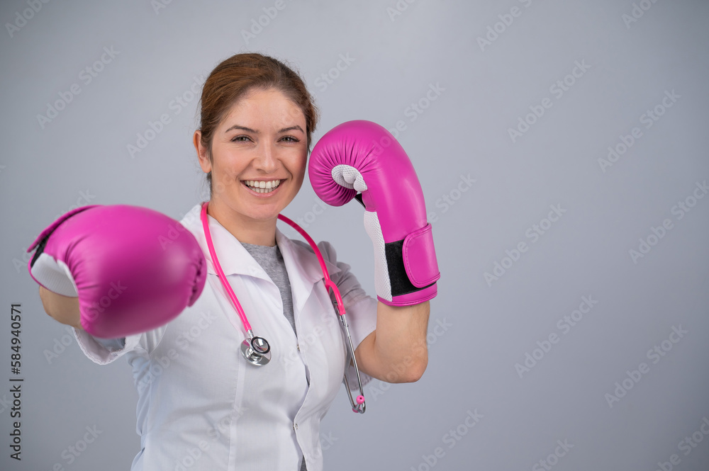 Woman doctor in pink boxing gloves on a white background. Woman doctor in pink boxing gloves on a white background.