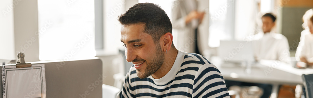 Obraz premium Businessman in casual clothes working laptop while sitting in modern office on colleagues background