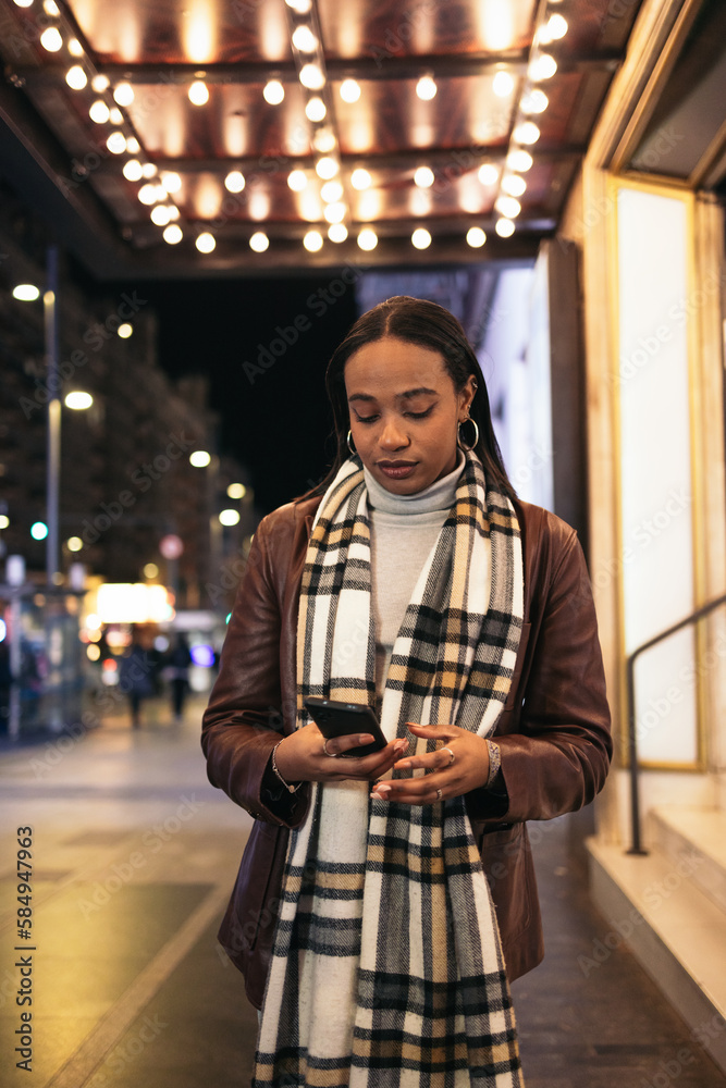 Black woman using smartphone in the city at night Black woman using smartphone in the city at night