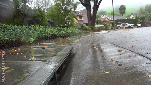 2023 - Excellent aerial footage of a storm drain catching rain waters outside a row of houses during a storm in Ventura, California. photo