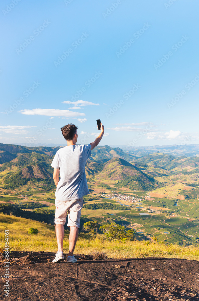 Traveler taking a selfie with his cell phone or smartphone to post on social media, with a landscape of mountains in the background. Traveler taking a selfie with his cell phone or smartphone to post on social media, with a landscape of mountains in the background.
