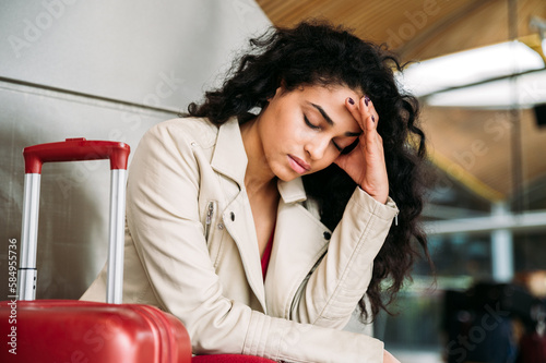 Upset woman sitting near luggage in airport