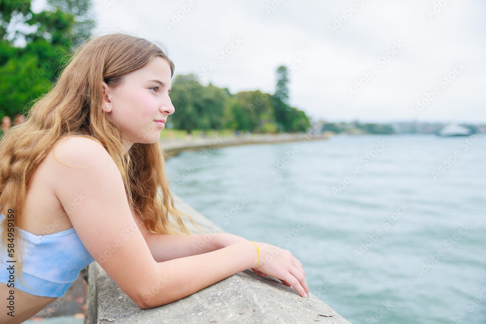 海で遠くを見つめるスポーツウエアを着た白人少女