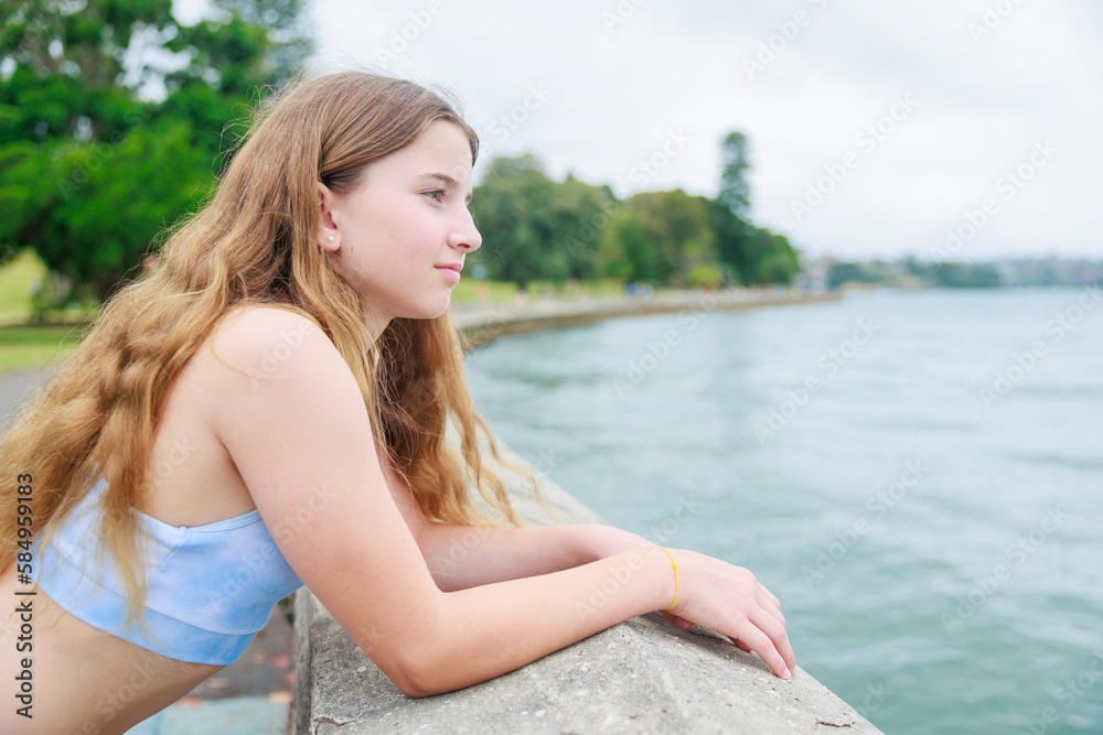 海で遠くを見つめるスポーツウエアを着た白人少女
