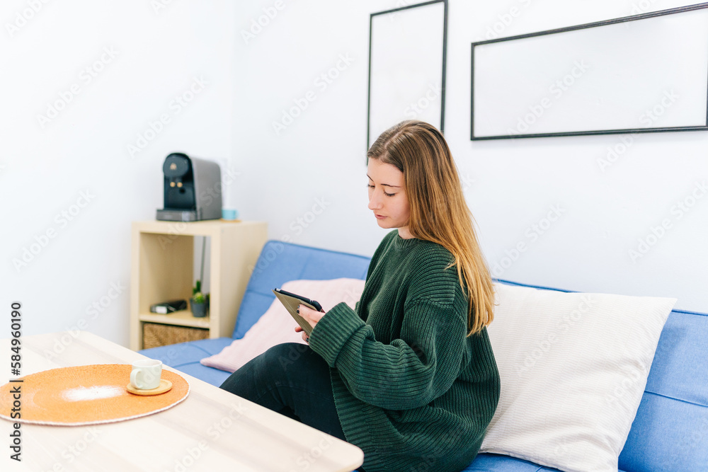 Focused woman working on tablet on sofa Focused woman working on tablet on sofa
