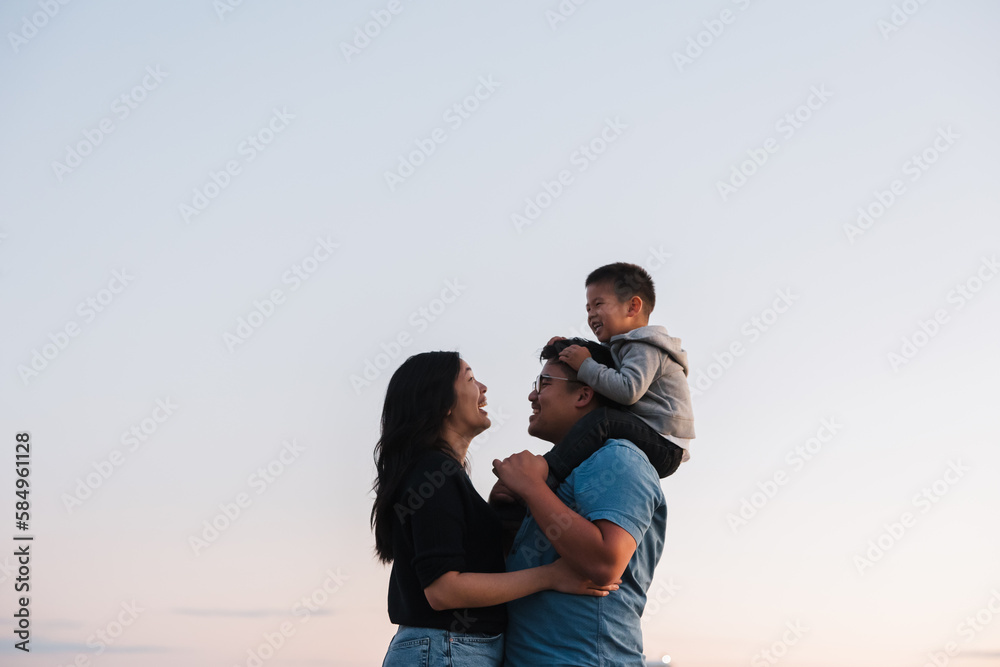 Family of three enjoying shoulder ride time together outside at Family of three enjoying shoulder ride time together outside at