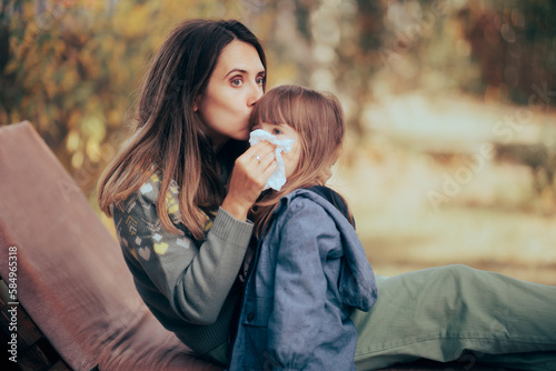 Loving Mom Wiping her Toddler Daughter Nose. Mother helping little girl with her runny nose problem in allergy season 