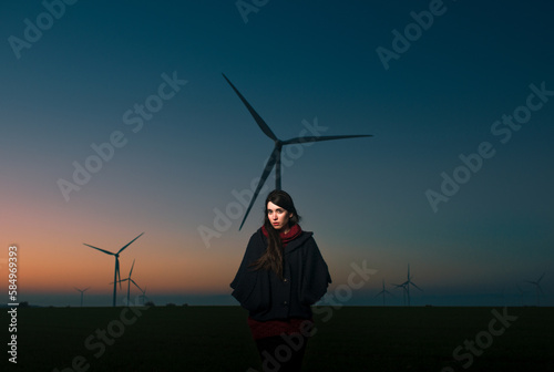 Dark portrait of standing woman with wind turbines photo
