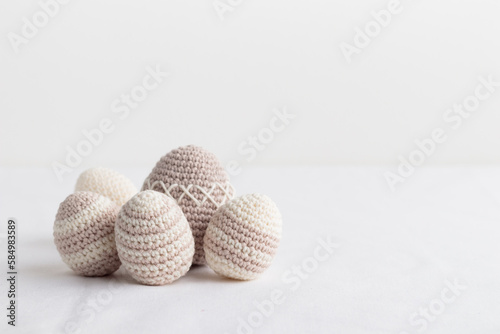 Set of cute handmade crocheted eggs, pastel colored on a white table