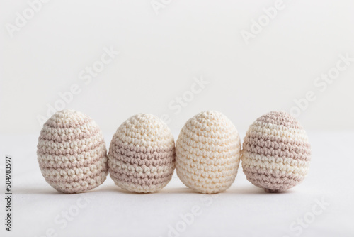 Row of cute striped pattern crocheted eggs, pastel color on a white