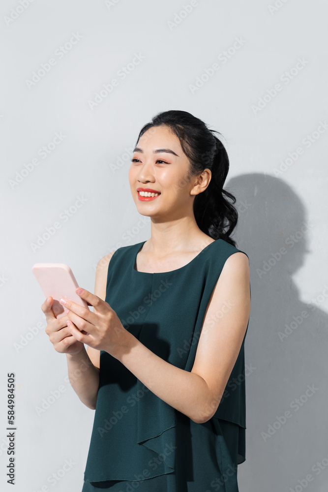 Smiling lovely young woman standing and using cell phone Smiling lovely young woman standing and using cell phone