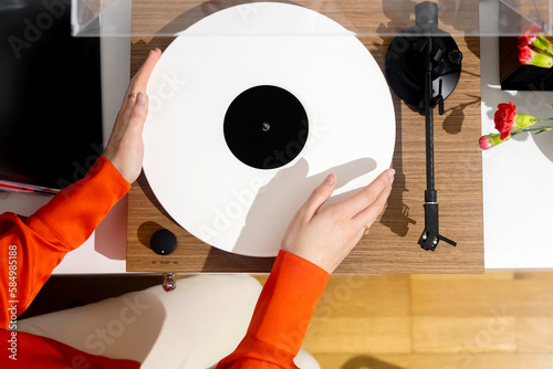 Hands install a vinyl record on a record player to listen to m
