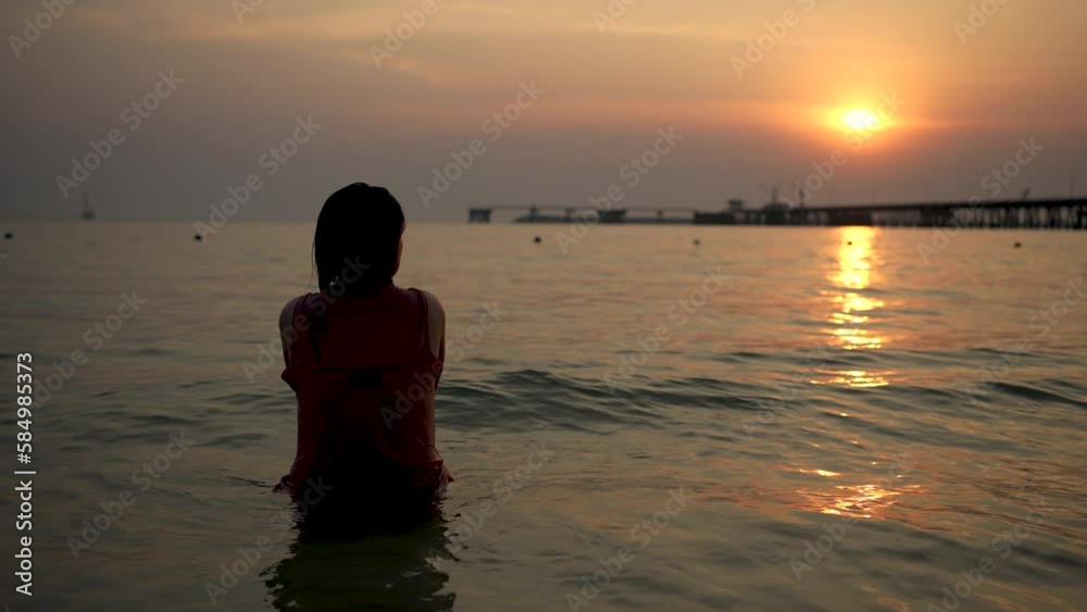A woman is happily watching the sunset in the sea. A woman is happily watching the sunset in the sea.