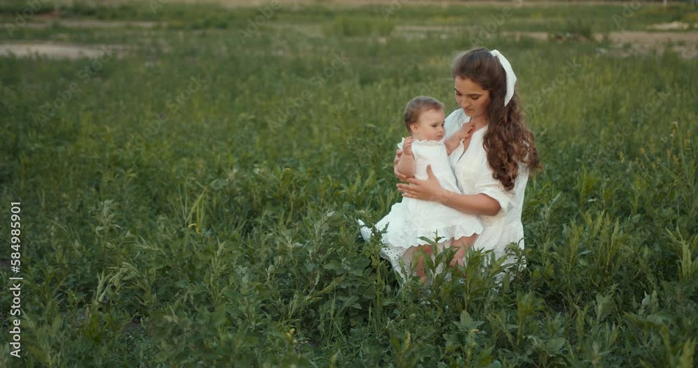 Beautiful mother holding her baby daughter in the summer field Beautiful mother holding her baby daughter in the summer field