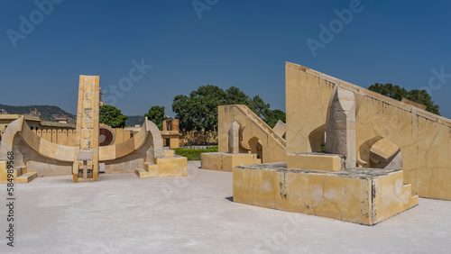 Ancient astronomical measuring instruments made of sandstone are located at the Jantar Mantar Observatory. Curved surfaces, stairs, geometric shapes against the blue sky. India. Jaipur