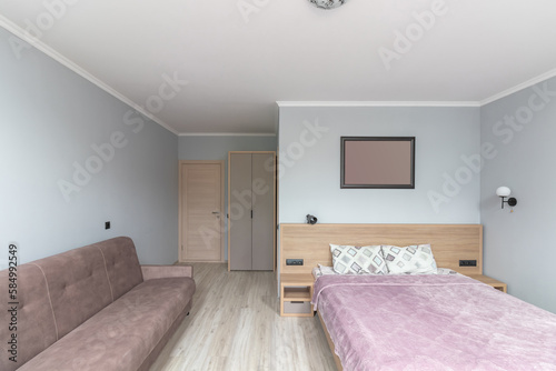 Hotel room with a large double bed in light colors