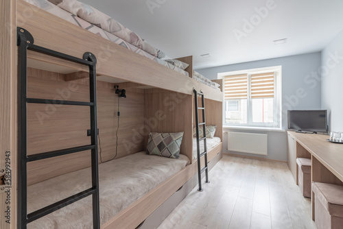 Hostel dormitory beds arranged in dorm room with white plain bunk bed in dormitory.Hostel dormitory have many beds arranged in one room. Clean hostel small room with wooden bunk beds. small hotel