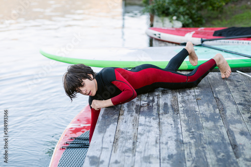 Teenage surfer enjoying in wetsuit in a lake