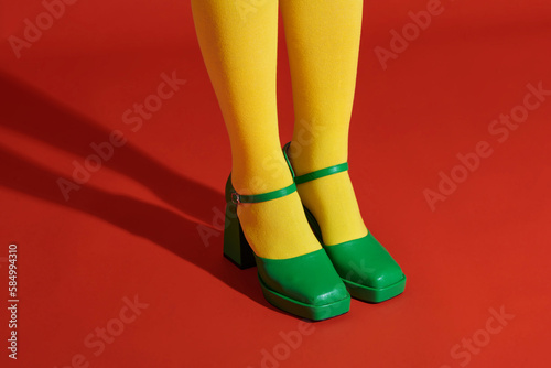 Legs of young woman in socks and sandals standing against photo