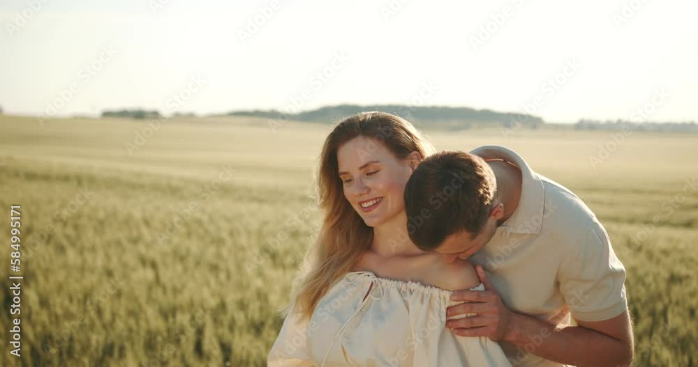 Pregnant woman standing with her husband hugging in the field Pregnant woman standing with her husband hugging in the field