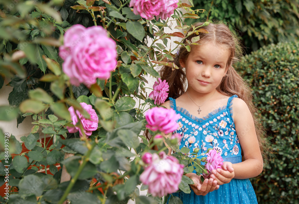 A beautiful happy little girl is sitting in a garden surrounded by flowers. A lovely baby in a blue dress smiles tenderly.
A beautiful happy little girl is sitting in a garden surrounded by flowers. A lovely baby in a blue dress smiles tenderly.
