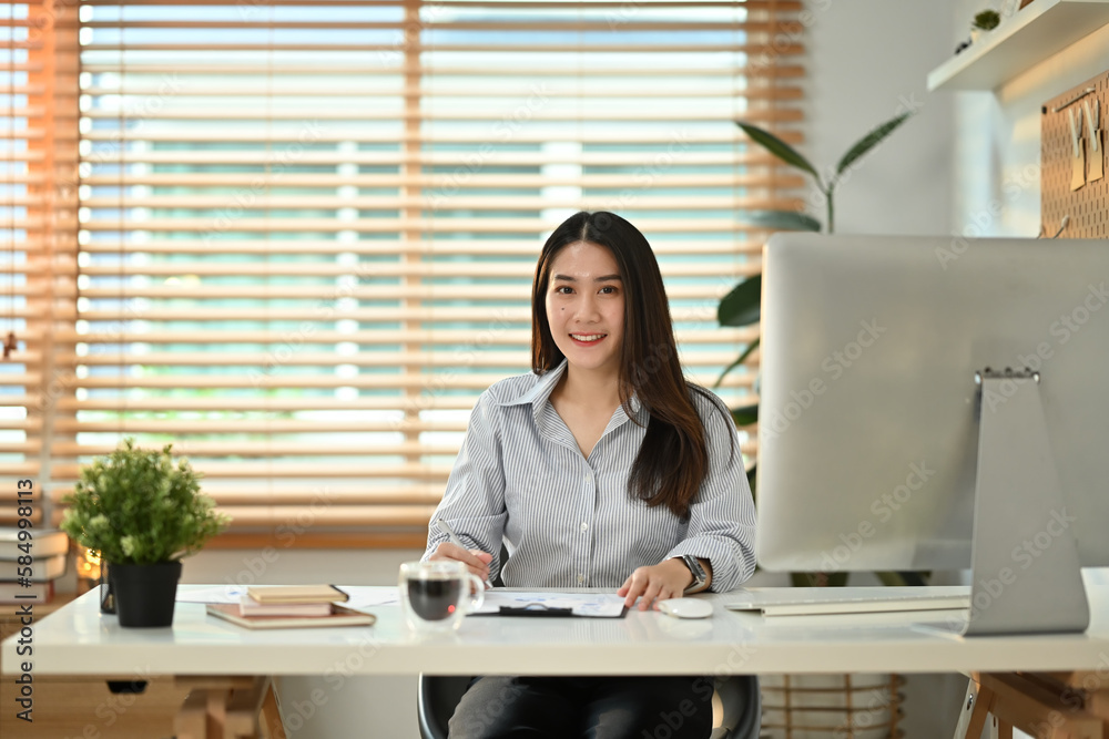 Attractive millennial businesswoman working with reports and analyzing statistics data online on computer screen Attractive millennial businesswoman working with reports and analyzing statistics data online on computer screen