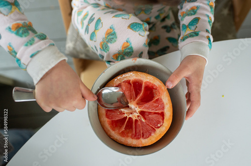 Child Eating Grapefruit for Breakfast at Home photo