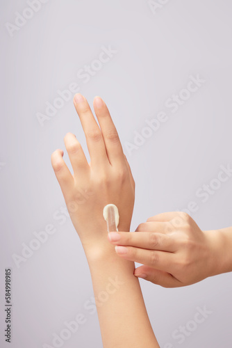 Hands of woman model applying cosmetic cream texture on her hand against a light background. Daily skincare and body care routine concept