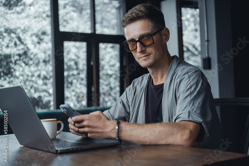 Young man using smartphone in hand, office,happy face, outdoor hipster portrait on the cafe, smile happy face, listen music on headphones, Amsterdam street, dance, player,photo concept, laptop