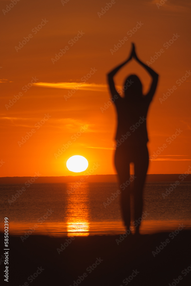 yoga meditation, silhouette of woman at sunset in pose tree with outstretched arms. health recreation and outdoor sports. poster, postcard. person is engaged in breathing practices. mental health