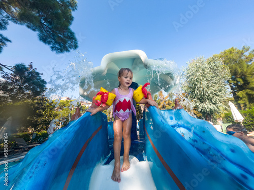 cute girl enjoying water slide during family vacation photo