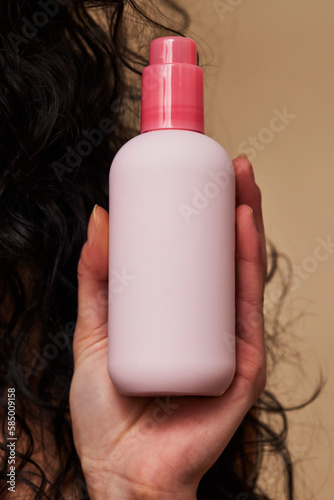Woman's hand holding pink skincare bottle
